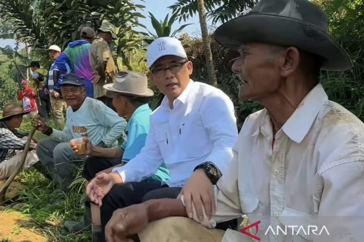 Kang Dadan duduk berbincang dengan para petani di kebun